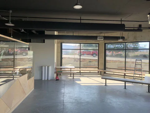 A bright, modern commercial interior in Port Alberni featuring professional electrical work, including halo-style pendant lighting, industrial ceiling conduits, and integrated counter lighting in a newly renovated café.