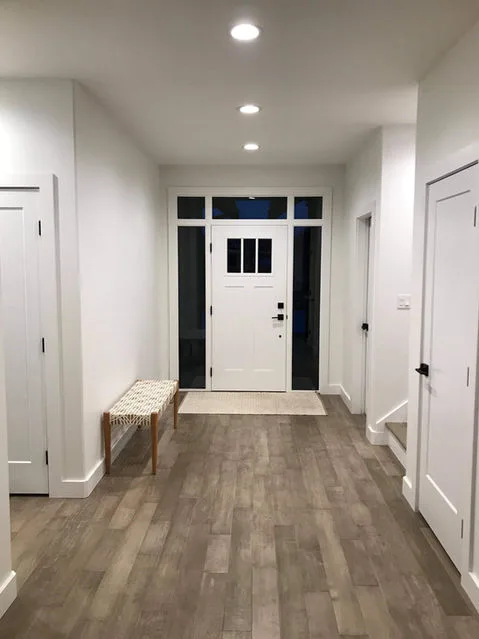 Pacific Coast Electric LTD. showcases a spacious, well-lit hallway with wooden flooring and a bench