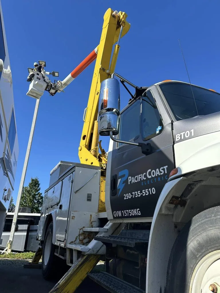 Electrical contractor using a cherry picker to reach a high sign for maintenance