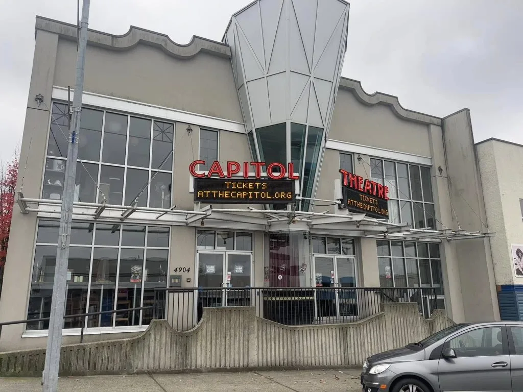 A modern theater facade features large windows and a distinctive geometric structure