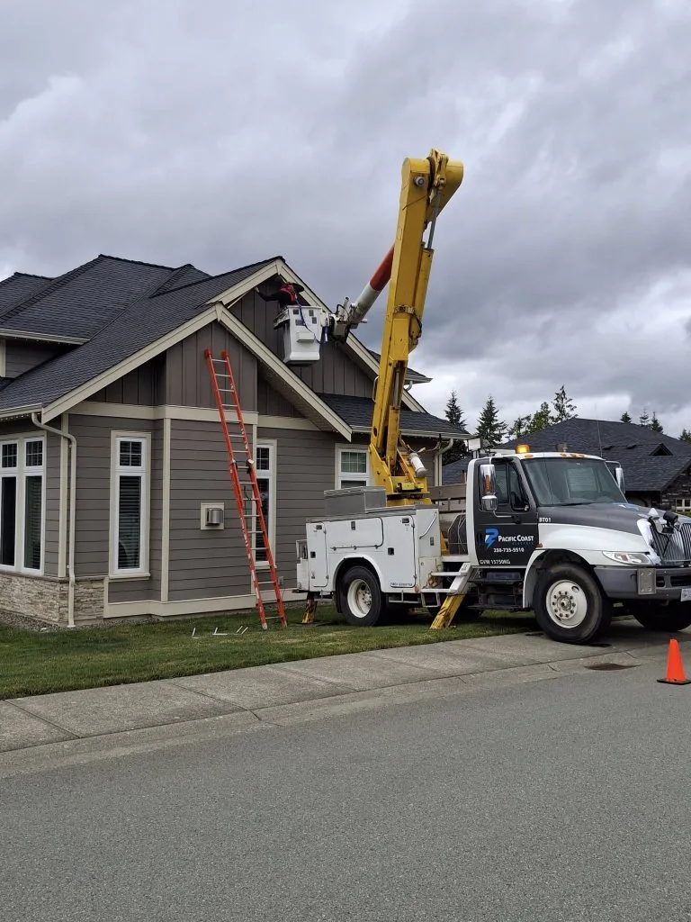 Residential roof work in progress with a crane and large vehicle