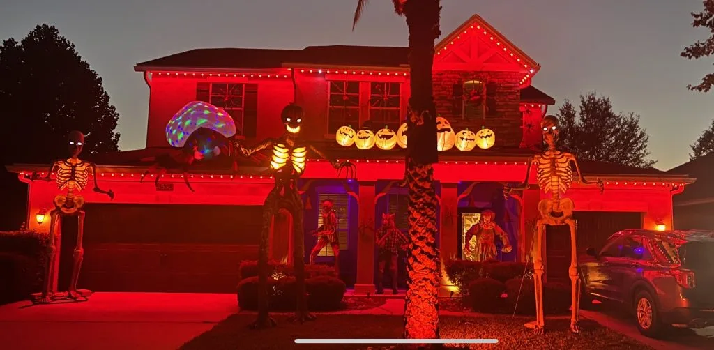 A house is decorated with glowing skeletons and colorful lights for Halloween