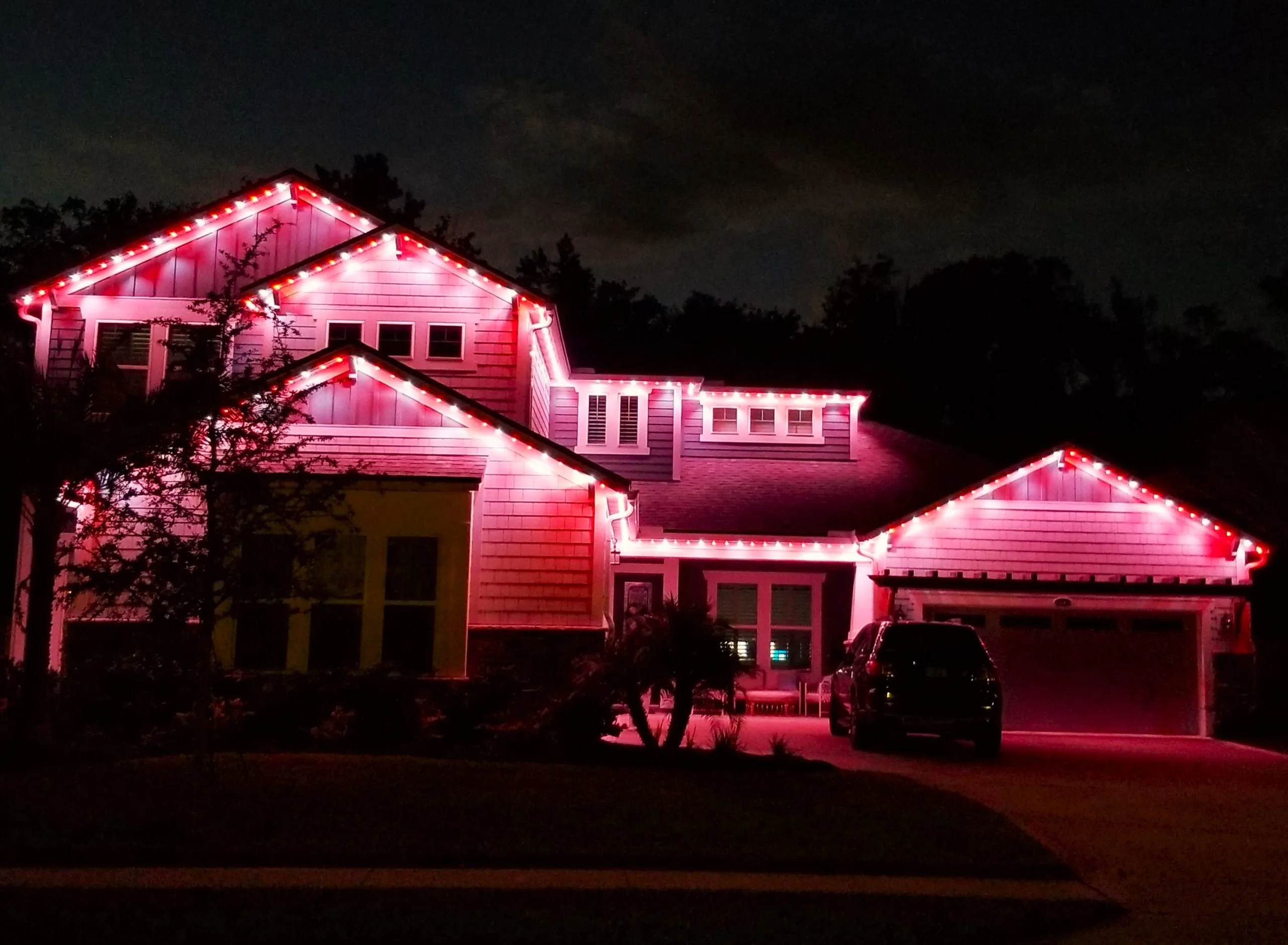 Gemstone Lights illuminate a house with vibrant pink hues at night