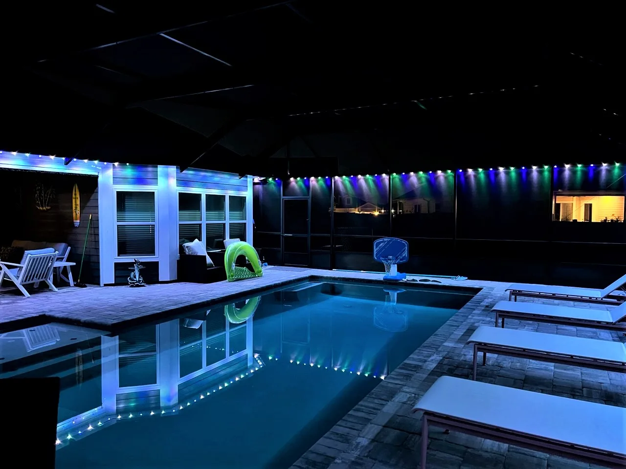 Gemstone Lights illuminate a stylish pool area with lounge chairs at night