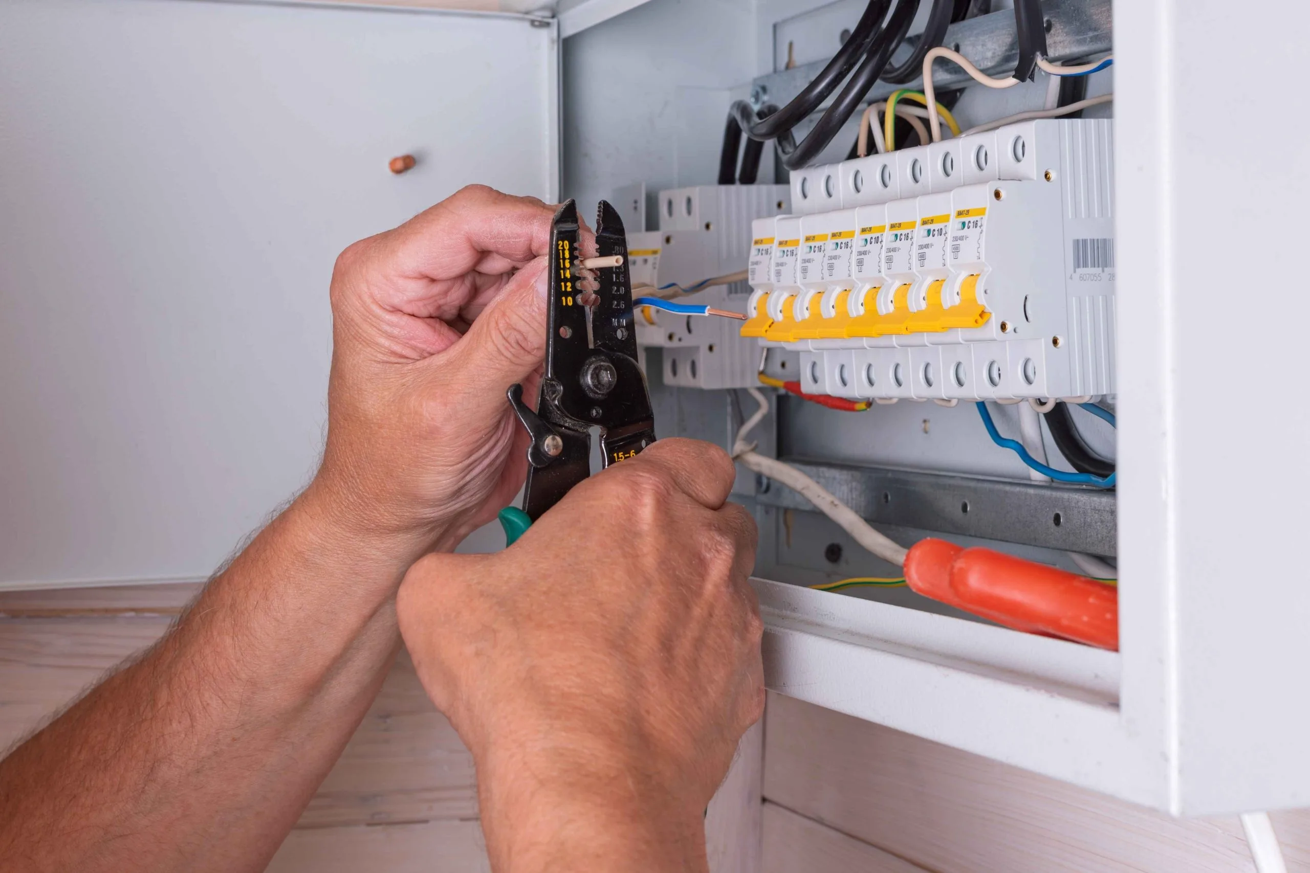 A technician performs house wiring upgrades using wire cutters on electrical connections