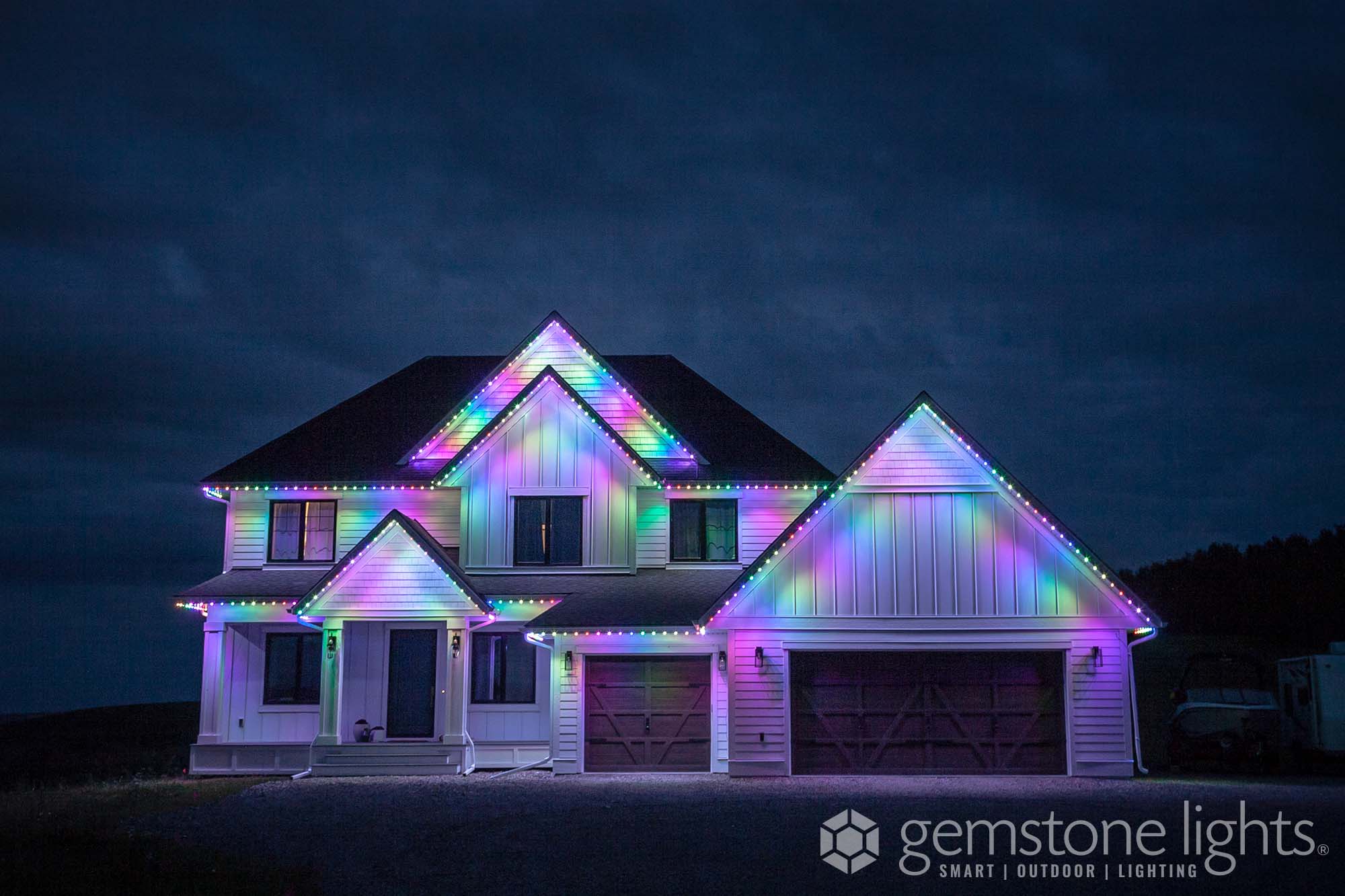 A brightly lit house glows with colorful holiday lights against a dark sky