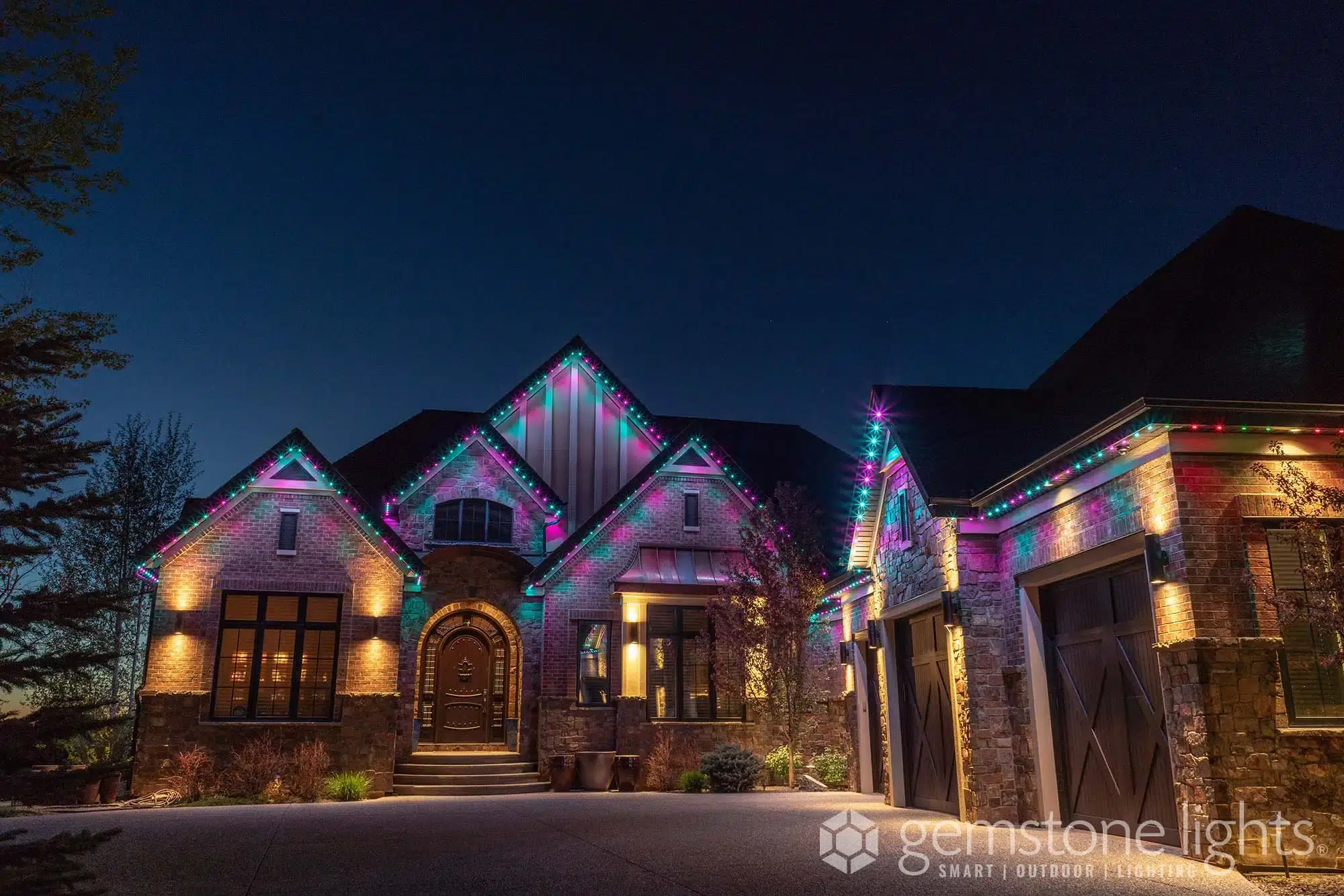 A beautifully decorated house is illuminated with colorful lights at dusk