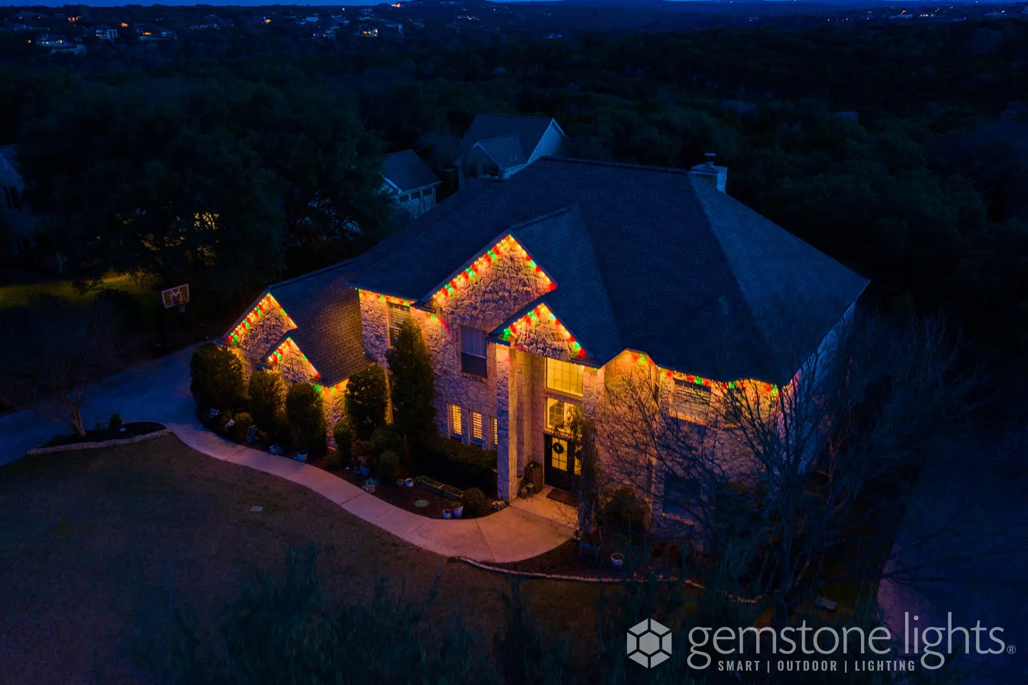 Warm, glowing lights accentuate a beautifully landscaped house at dusk