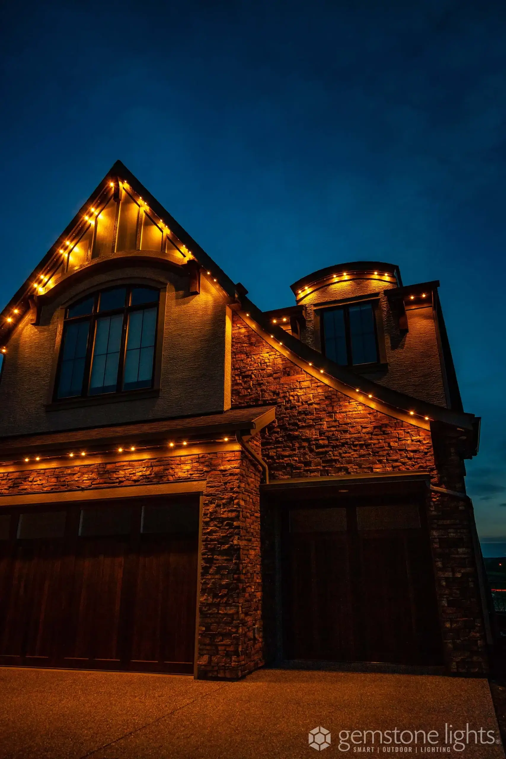 Soft, warm lights adorn a beautifully designed home against a twilight sky