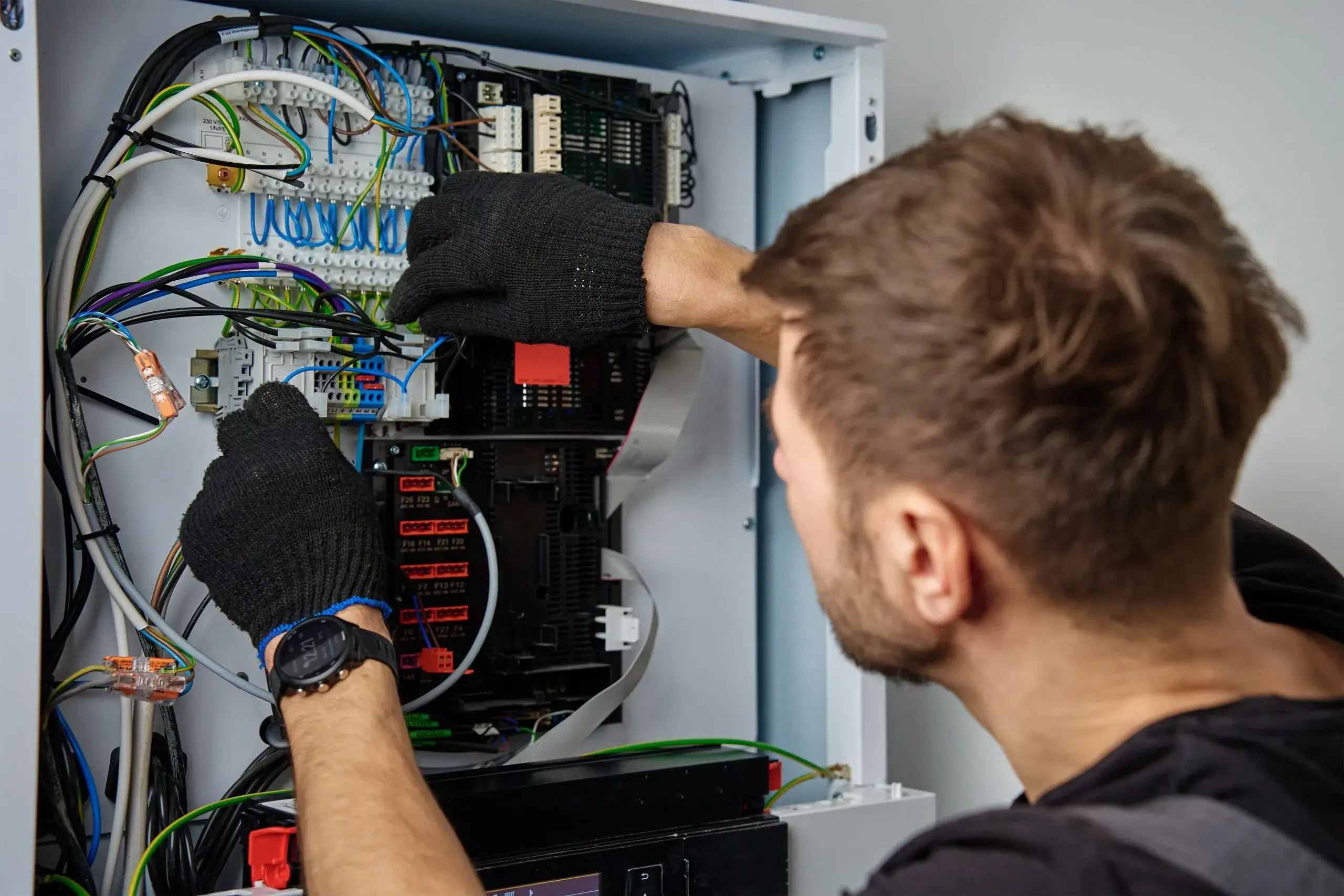 A technician is wiring and adjusting connections inside an electrical panel